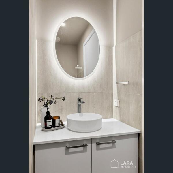 Contemporary powder room with feature mirror and modern vanity in a custom new home in Lara