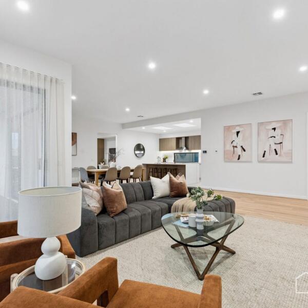 Open-plan living area connecting seamlessly to kitchen and dining spaces in a custom home build Lara